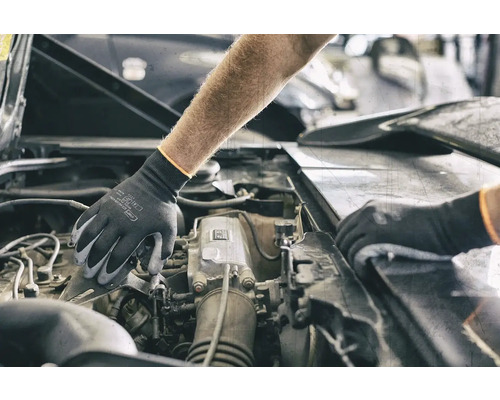 Een persoon met beschermende handschoenen werkt aan een automotor.