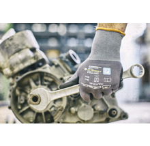 Hand met werkhandschoen en moersleutel aan een motor