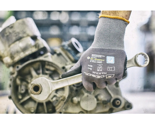 Hand met werkhandschoen en moersleutel aan een motor