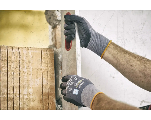 Man met werkhandschoenen en waterpas tijdens renovatiewerkzaamheden.