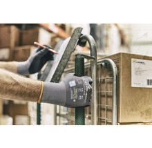 Een persoon met werkhandschoenen duwt een rolwagen.