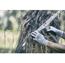 Persoon met handschoenen die droog gras oppakt met een houten hark