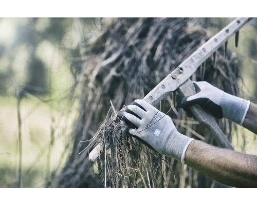 Persoon met handschoenen die droog gras oppakt met een houten hark