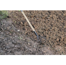 Drietandige tuinkrabber met houten handvat in de tuinbodem