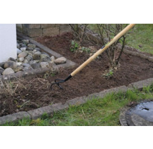 Tuinscène met een grondtand met houten handvat bij de grondbewerking