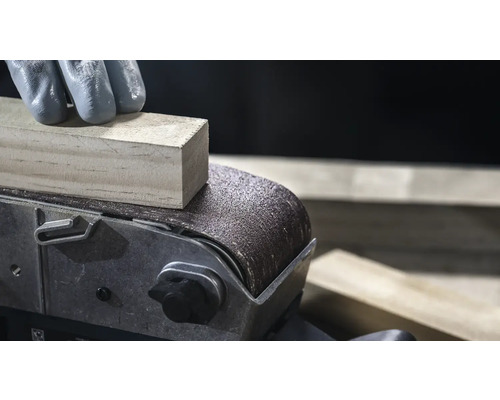 Close-up van een bandschuurmachine die een stuk hout gladmaakt