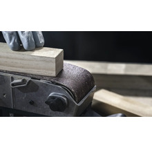 Close-up van een bandschuurmachine die een stuk hout gladmaakt