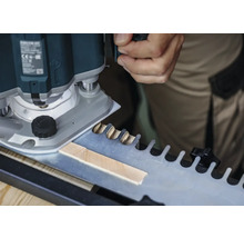 Een bovenfrees bij het bewerken van een werkstuk met een sjabloon voor vingerlasverbindingen.