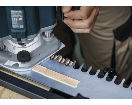 Een bovenfrees bij het bewerken van een werkstuk met een sjabloon voor vingerlasverbindingen.