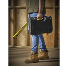 Een persoon draagt een gereedschapskist en een waterpas van Stanley.