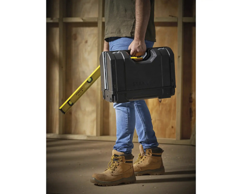 Een persoon draagt een gereedschapskist en een waterpas van Stanley.