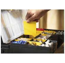 Open gereedschapskist met verschillende vakken en een hand die een geel inzetstuk vasthoudt.