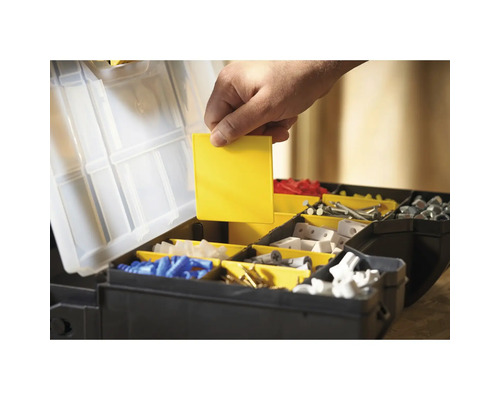 Open gereedschapskist met verschillende vakken en een hand die een geel inzetstuk vasthoudt.