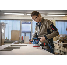 Vrouw schuurt houten plaat met een excentrische schuurmachine