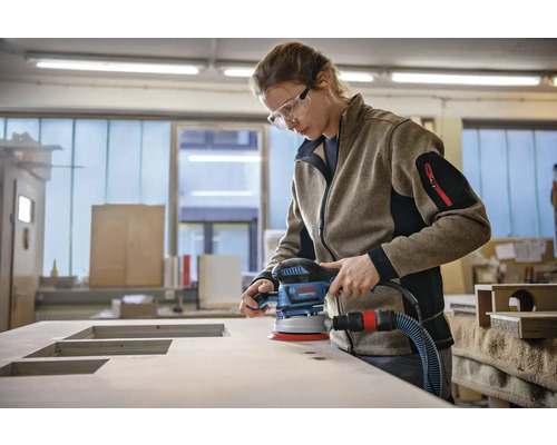 Vrouw schuurt houten plaat met een excentrische schuurmachine
