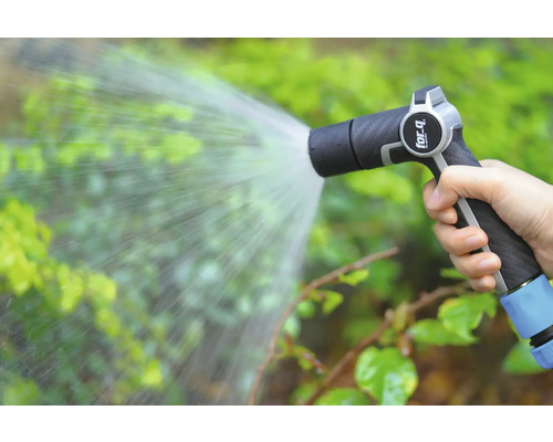 Een hand houdt een tuinspuit vast die water op planten spuit