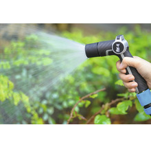 Een hand houdt een tuinspuit vast en besproeit planten.