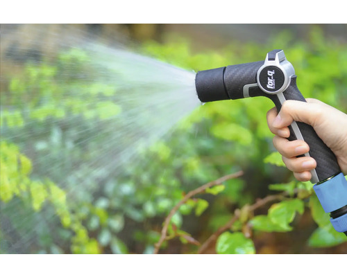 Een hand houdt een tuinspuit vast en besproeit planten.