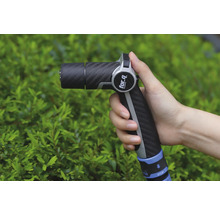 Een hand houdt een tuinspuit van het merk For Q vast voor een groene struik