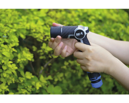 Een persoon houdt een for_q tuinspuit vast voor een groene struik.