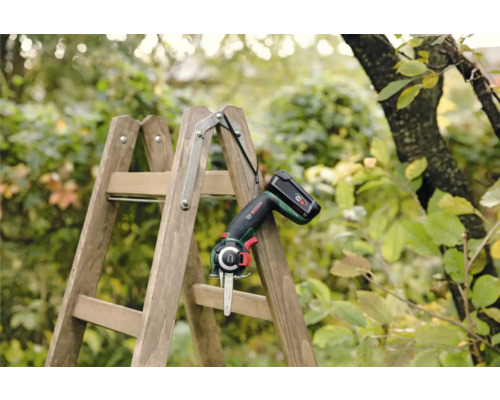 Accu-tuinzaag op houten ladder in de tuin