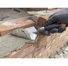 Metselaar legt baksteen met een troffel op een bouwplaats