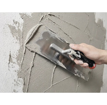 Metselaar stucwerkt muur met een pleisterspaan