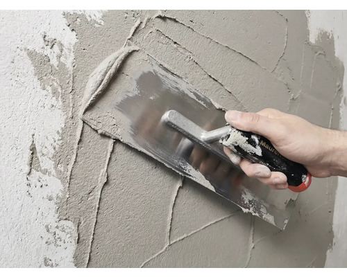 Metselaar stucwerkt muur met een pleisterspaan