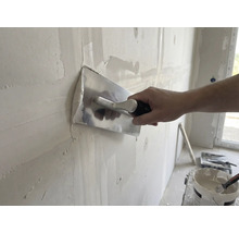 Ambachtsman maakt wand glad met gladde troffel en pleister