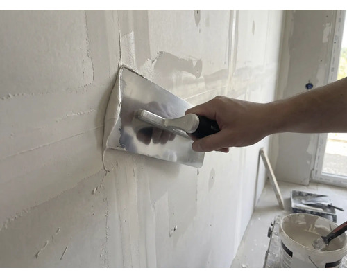 Ambachtsman maakt wand glad met gladde troffel en pleister