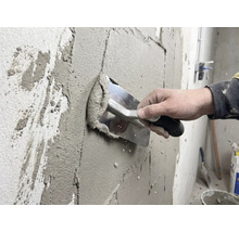 Ambachtsman brengt stuc aan op een muur met een spaan.