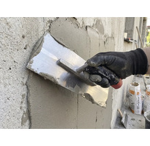 Ambachtsman maakt stucwerk glad met een pleisterspaan op een muur.