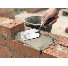 Metselwerk: Baksteen wordt gevoegd met mortel en een troffel.
