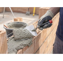 Metselaar die mortel en bakstenen verwerkt voor de bouw van een muur