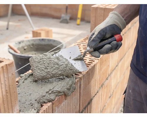 Metselaar die mortel en bakstenen verwerkt voor de bouw van een muur