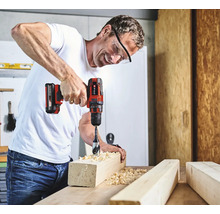 Man boort een gat in een stuk hout met een accuschroefboormachine