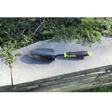 Tuinschep op een muur met planten op de achtergrond