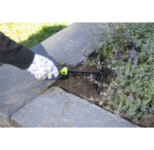 Een persoon gebruikt een tuinkrabber om de aarde in een verhoogde tuin los te maken.