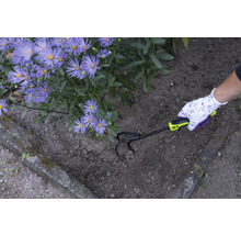 Een tuinman maakt de grond los met een cultivator naast paarse bloemen.