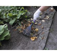 Iemand harkt bladeren met een bladhark in de tuin.
