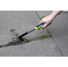 Een hand gebruikt een voegenkrabber om onkruid te verwijderen tussen bestratingstenen.