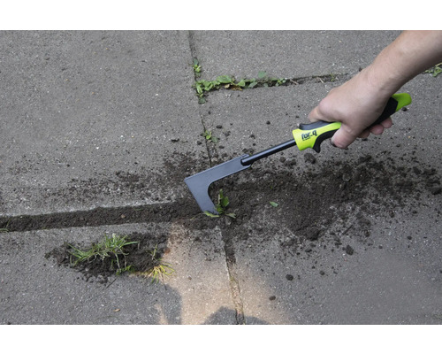 Een persoon verwijdert onkruid met een voegenkrabber op een verhard oppervlak.