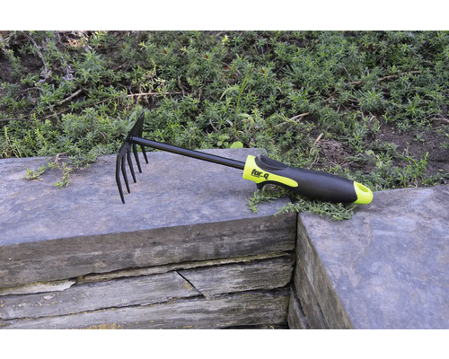 Blad- en tuinhark met tanden en kunststof handvat op stenen muur