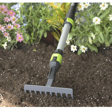Kleine tuinhark met grijze metalen kop en verstelbare telescopische steel in donkere aarde voor bloemen.