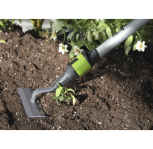 Tuinschoffel met grijs blad en groene aansluiting bij het wieden van onkruid in donkere aarde naast een plant.