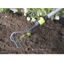 Tuinschoffel van metaal bij het werken in de grond naast een plant.