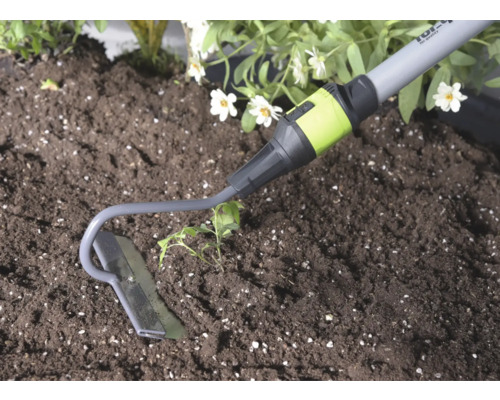 Tuinschoffel van metaal bij het werken in de grond naast een plant.