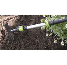 for_q tuinhak en hark combinatie met telescoopsteel bij het tuinieren in aarde naast bloemen.