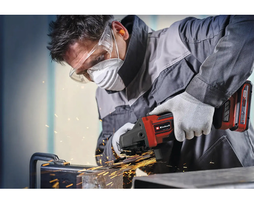 Vakman werkt met Einhell accu-haakse slijper op metaal met vonken, draagt een veiligheidsbril, stofmasker, gehoorbescherming en handschoenen.