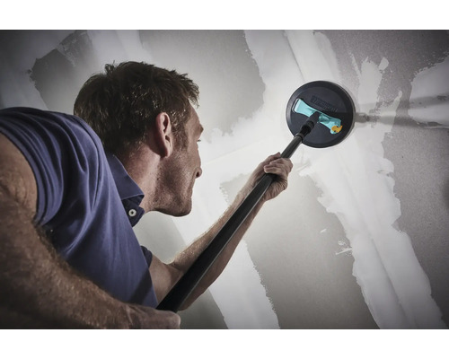 Een man schuurt een gipsplaten muur met een langnek schuurmachine.